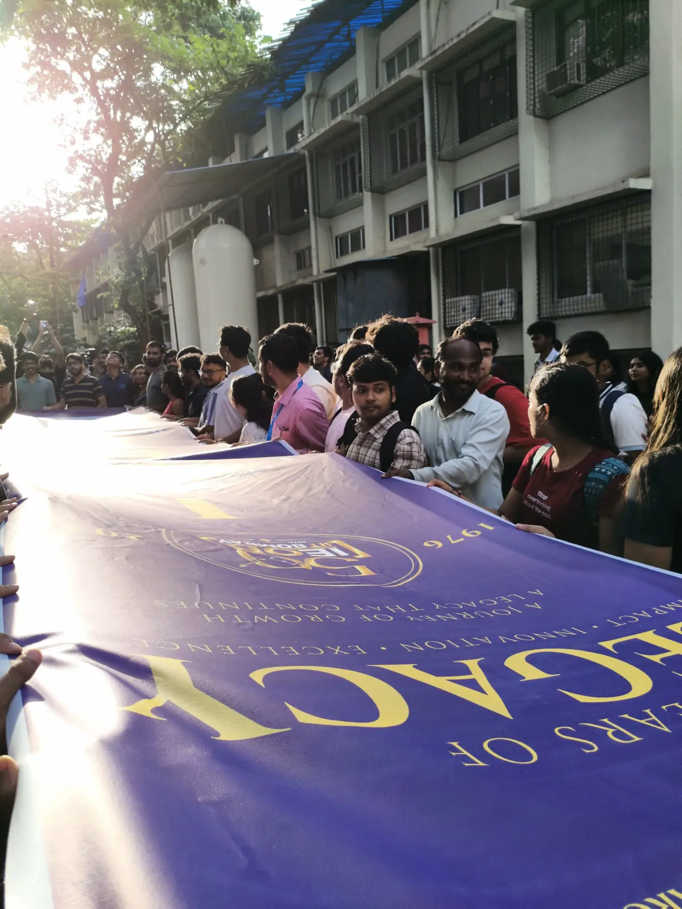 Students and faculty holding a long purple Golden Jubilee banner