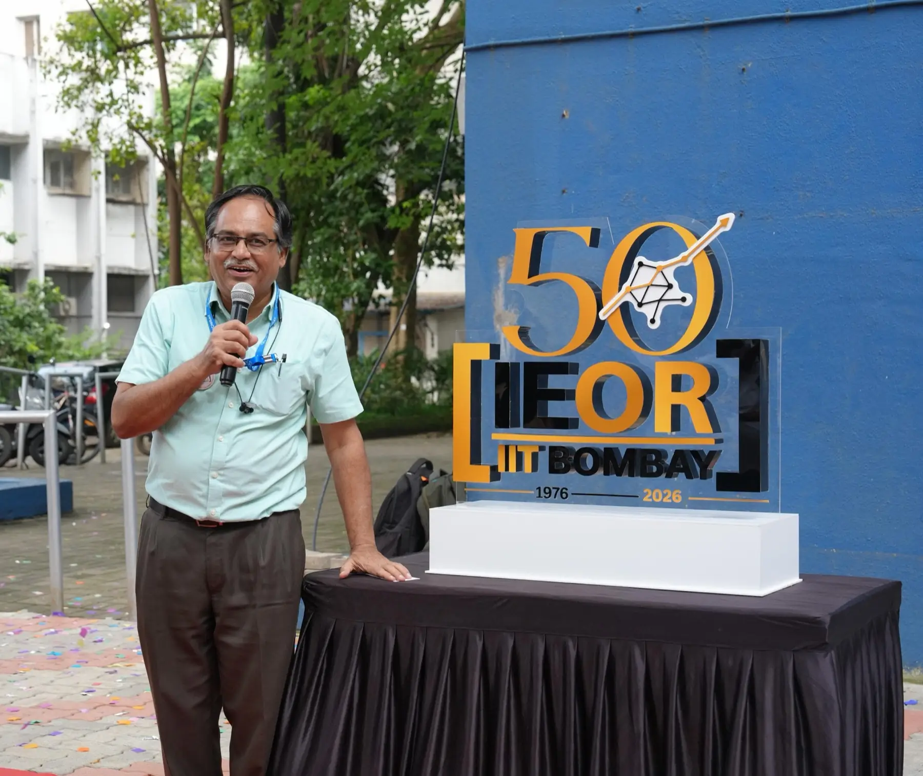 The Golden Jubilee mark on a table outside the IEOR building, beside a faculty member with a microphone