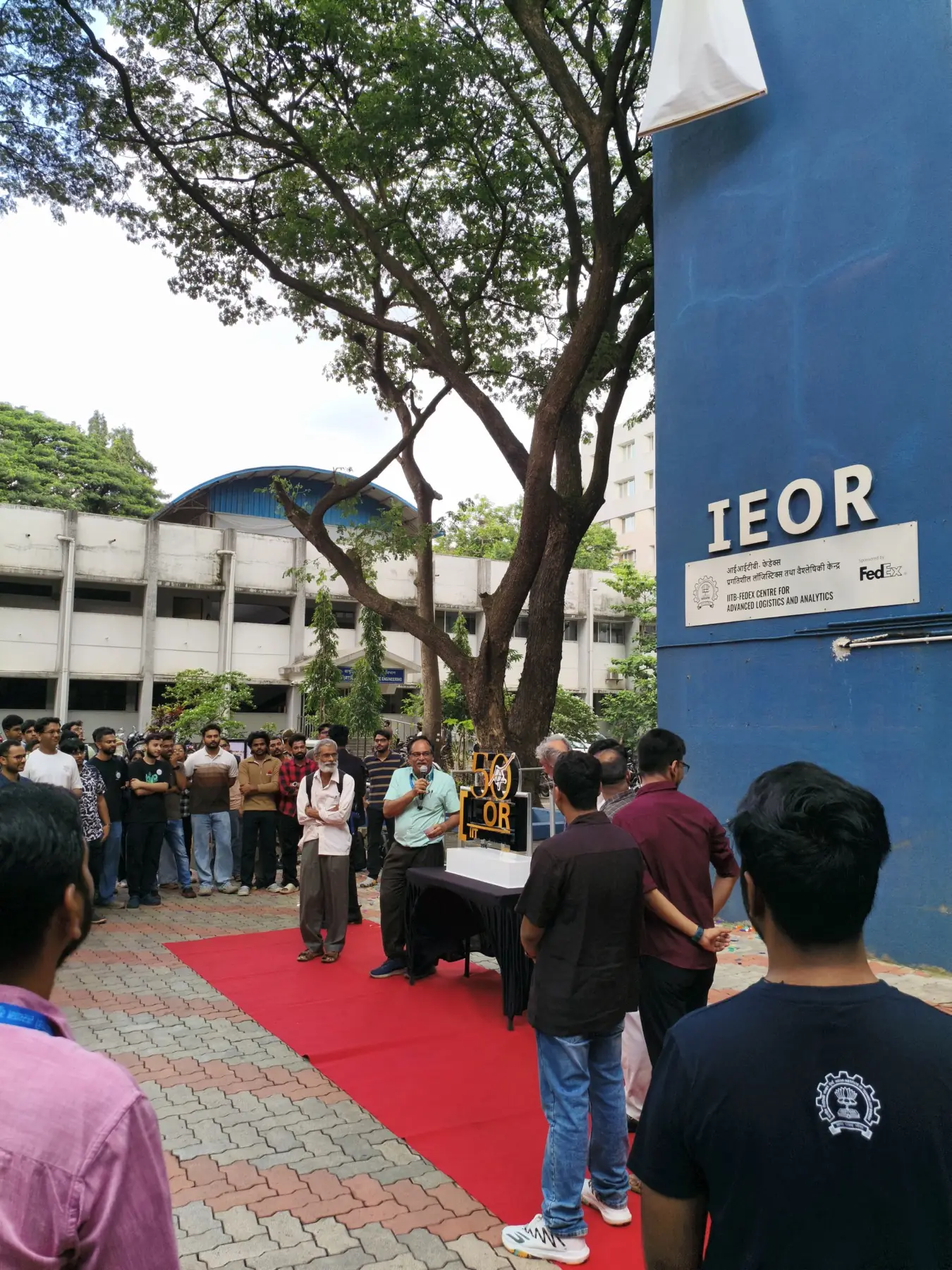 Faculty and students gathered on a red carpet around the Golden Jubilee mark